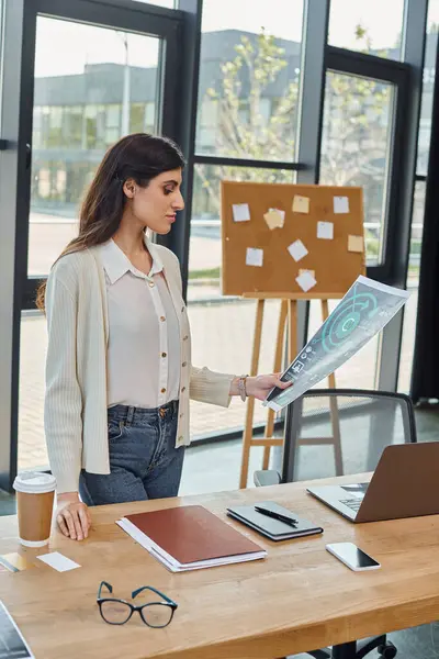 彼女のチャートに焦点を当てた近代的なオフィスに立っているビジネスマン — ストック写真