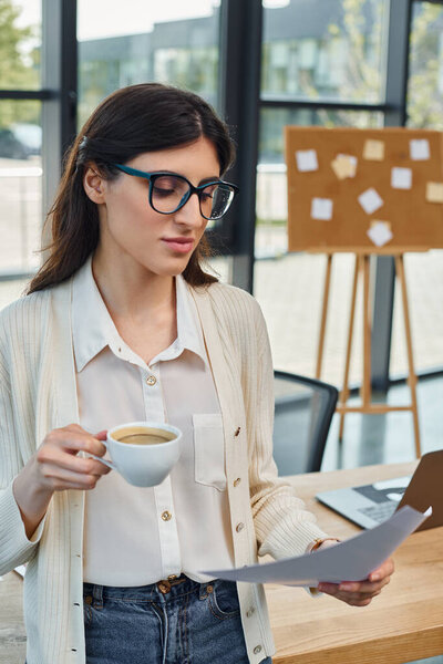 Деловая женщина в современном офисе держит чашку кофе, отдыхает от работы.