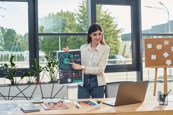 一位女商人自信地站在一个现代化的办公室里 举着一个标牌 在一个特许经营权概念的背景下传达她的信息 — 图库照片