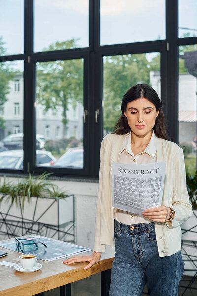 A businesswoman stands by a table, holding a contract, in a modern office setting representing a franchise concept.