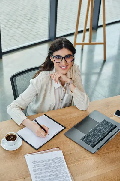 一位女商人陷入沉思 坐在桌子旁 在现代化的办公室里拿着笔记本和钢笔 — 图库照片