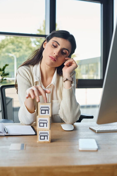 Женщина сидит за своим столом в современном офисе, рядом со стопками блоков на деревянном столе, представляя концепцию франшизы.