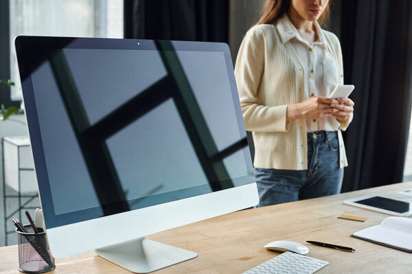 A businesswoman stands in a modern office, examining data on a computer screen linked to a franchise concept.