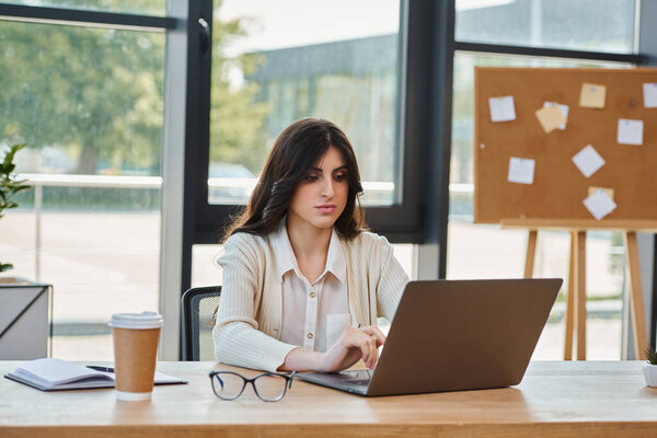 A businesswoman immersed in a laptop at her modern office table, strategizing for a franchise venture.