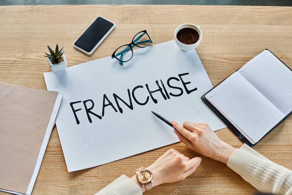 A businesswoman sitting at a table with a sign that says franchise in a modern office setting.