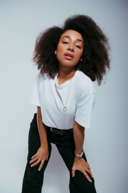 Çekici Afro-Amerikan kadın şık giyinmiş, kıvırcık saçlı, kameraya bakıyor, moda kavramı