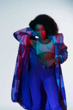 Sütyen ve sahte kürklü seksi Afro-Amerikalı kadın kırmızı ve mavi ışıklarla çevrili kameraya bakıyor.