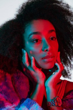 Sahte kürklü çekici Afro-Amerikan kadın modeli ışıklara bakıyor, moda konsepti