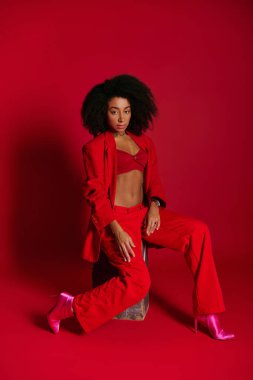 Çekici, seksi, Afro-Amerikalı, kırmızı elbiseli, oturan ve kameraya bakan, moda konsepti