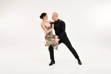 Genç bir adam ve bir kadın akrobatik bir şekilde dans ediyorlar beyaz bir stüdyo arkaplanının karşısında.
