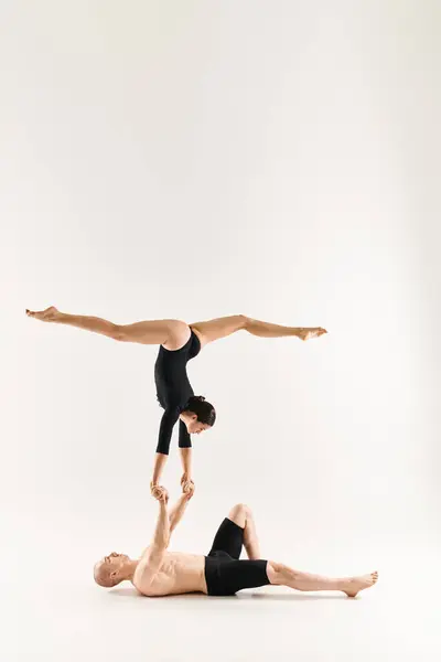 stock image Shirtless young man and dancing woman defy gravity in a synchronized handstand pose against a white studio backdrop.