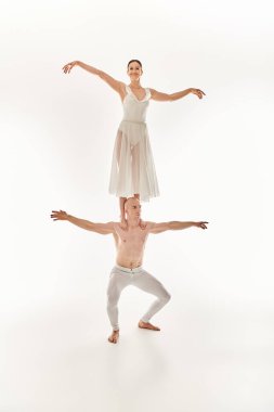Shirtless young man and woman in a white dress gracefully dance, showcasing acrobatic balance. clipart