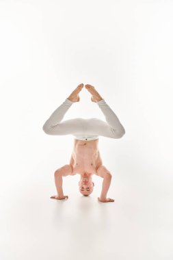 A young man showcases his acrobatic skills by performing a headstand, captured in a studio against a white background. clipart