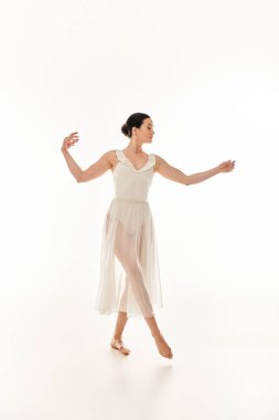 A young woman gracefully dances in a long white dress in a studio setting against a white background. clipart