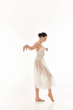 A young woman gracefully dances in a flowing white dress on a white background in a studio setting. clipart