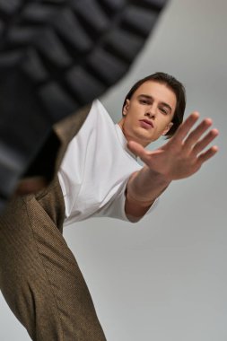 Gri arka planda hareketli şık giyinmiş şık bir adam, moda anlayışı.