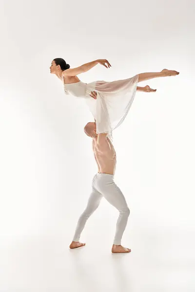 一个赤身裸体的年轻人和一个穿着白色衣服的女人在一个白色的工作室背景下优雅地共舞 融合了杂技元素 — 图库照片