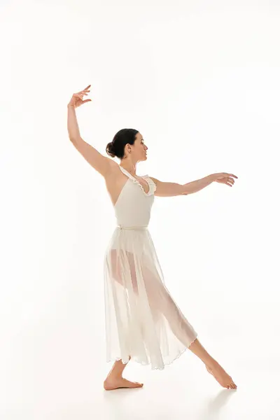 stock image A graceful young woman in a flowing white dress expresses the beauty of movement through dance.