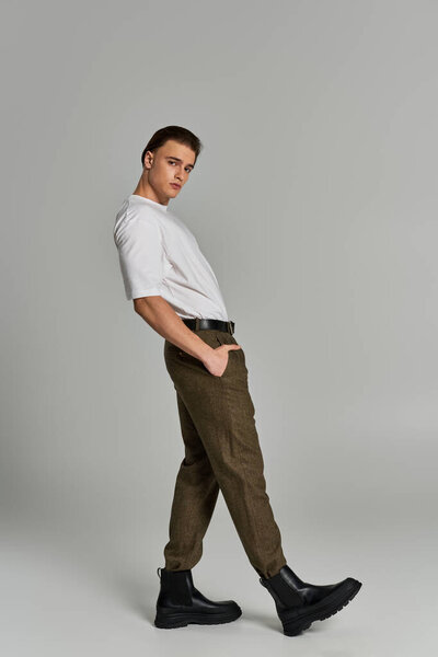 handsome sophisticated man in elegant attire with brown pants posing and looking at camera