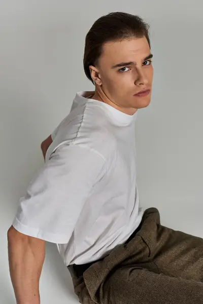 stock image appealing polished young man in stylish clothing sitting on gray background and looking at camera