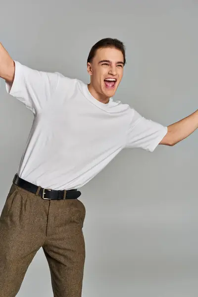 stock image joyous elegant male model in stylish attire posing in motion and looking away on gray backdrop