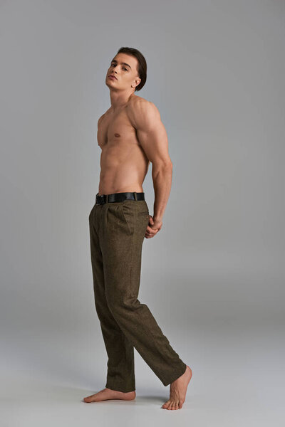 tempting young shirtless male model in elegant pants posing alluringly and looking at camera