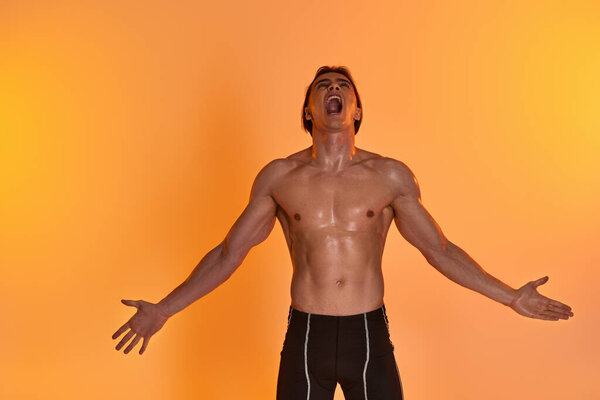 привлекательный молодой мужчина без рубашки выражает себя эмоционально на ярком оранжевом фоне