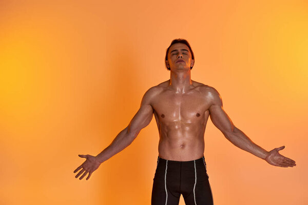привлекательный молодой мужчина без рубашки выражает себя эмоционально на ярком оранжевом фоне