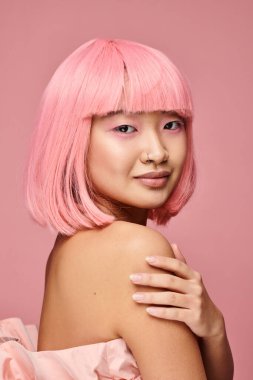 Güzel Asyalı kadın, burun piercingli, pembe saçlı, parlak arka planda gülümseyen.