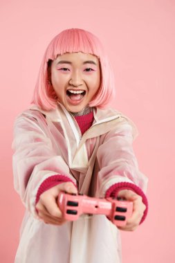 20 'li yaşlarda şık giyinmiş güzel Asyalı bir kadın neşeli arka planda joystick çalarken mutlu oluyor.