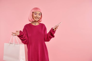 Pembe saçlı ve makyajlı çekici Asyalı kız canlı arka planda online alışveriş yapıyor.
