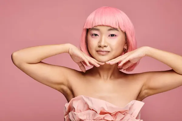 pretty asian woman with pink makeup hair and looking to side with hands on vibrant background