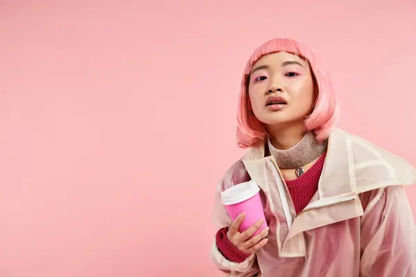stock image attractive asian girl in her 20s with pink hair posing with cup of coffee on vibrant background