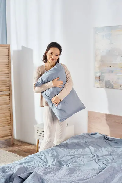 女性は愛情を持って暖かく居心地の良い寝室の設定で枕を保持し 家族の間の快適さとケアを象徴しています — ストック写真