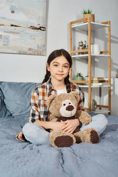 一个女孩舒服地坐在床上 把一只泰迪熊抱在胸前 享受着宁静祥和的时光 — 图库照片