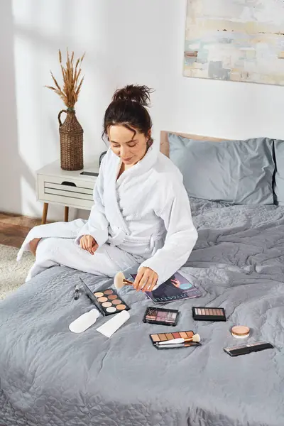 Brunette Woman White Bathrobe Sits Bed Bedroom Applying Makeup Surrounded — Stock Photo, Image