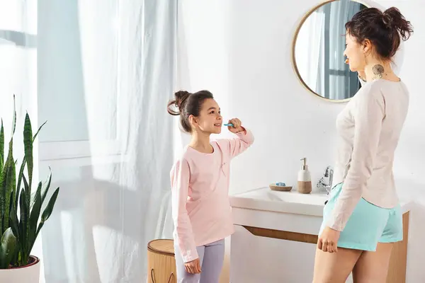 Brunette Nainen Harjaa Hampaansa Kun Hänen Tyttärensä Katselee Moderni Kylpyhuone — kuvapankkivalokuva