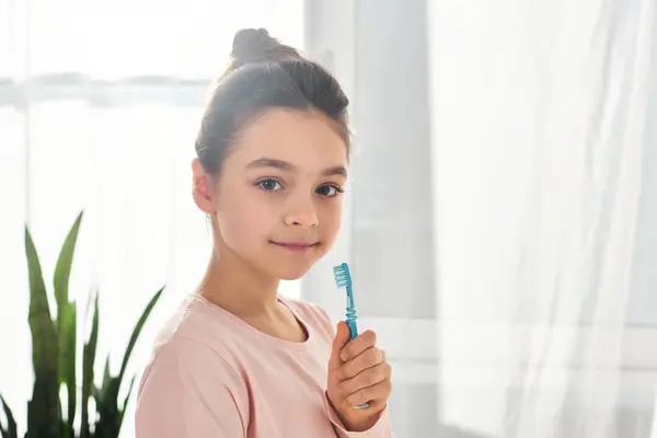 一个在现代浴室里拿着牙刷的黑发少女 强调卫生习惯的重要性 — 图库照片