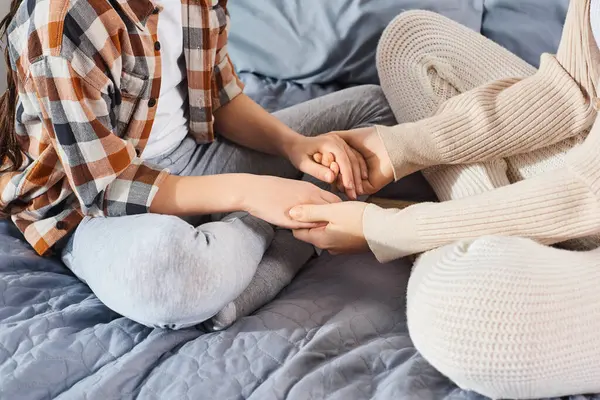 ベッドの上に座っている母と娘 接続と愛の柔らかい瞬間に手を握る — ストック写真