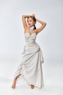 elegant asian young woman in bridal outfit looking to down and putting hands behind head clipart