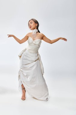 attractive asian young girl in bridal outfit look to side and spread arms to sides clipart