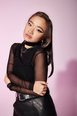 Kahverengi saçlı, ağır makyajlı güzel bir Asyalı kadın başını eğip kendine sarılıyor.