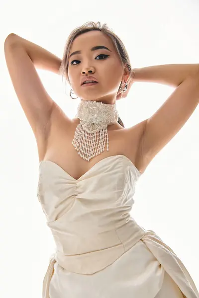 カメラを探しているブライダル衣装の魅力的なアジアの若い女性と頭の後ろに手を置く — ストック写真