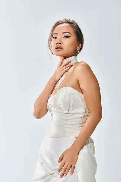 20多岁的漂亮的亚洲新娘用手把项链罩在浅色的背景上 — 图库照片