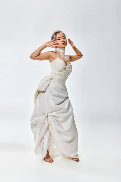 迷人的亚洲新娘 身穿白色优雅的礼服 双手紧挨脸庞 背景浅薄 — 图库照片
