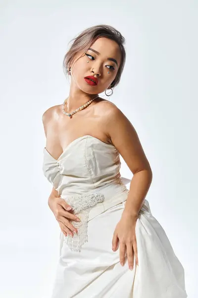 stock image attractive asian bride with red lipstick and pearl necklace looking behind back on white background