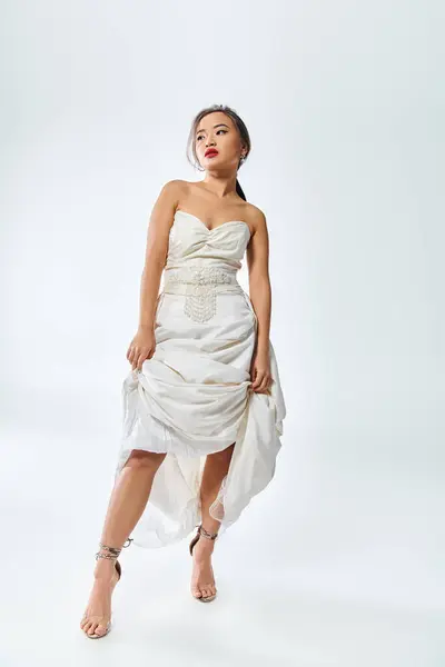 身穿红唇白色雅致服装的迷人的亚洲女人提起她的裙子 朝旁边看去 — 图库照片