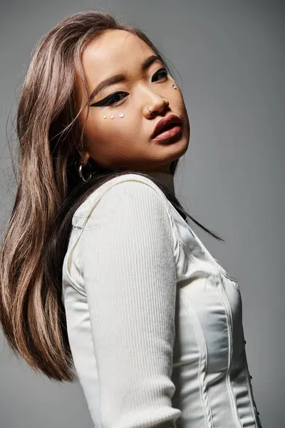 stock image beautiful asian woman in her 20s sideways looking to camera against grey background