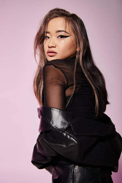 привлекательная азиатка 20 лет с дерзким макияжем, смотрящая в камеру сзади