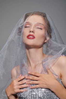 A young woman exudes classic beauty while posing in a studio, wearing a veil on her head. clipart